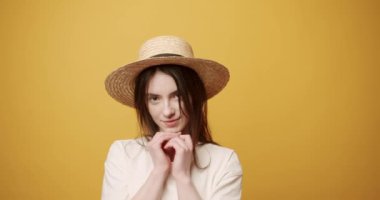 Güzel gözlü güzel bir kadın, sarı arka planda saçları var.