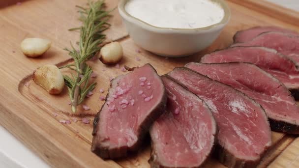 Grillat sällsynt medelnötkött kött med vitlök och rosmarin i en trägolv. — Stockvideo