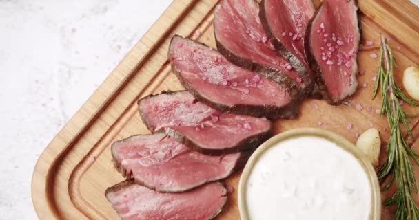 Grillat sällsynt medelnötkött kött med vitlök och rosmarin i en trägolv. — Stockvideo