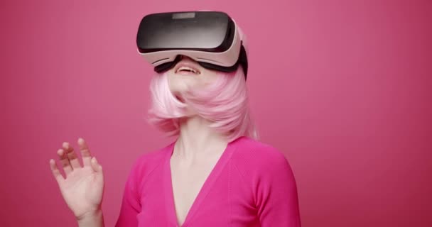 Žena používá brýle virtuální reality na izolovaném růžovém pozadí — Stock video