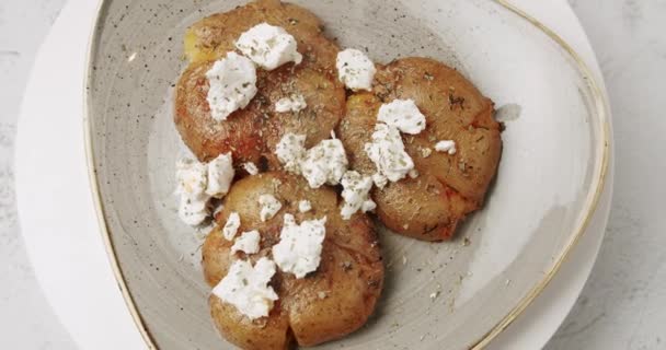 Batatas assadas na hora com queijo feta rodando em prato branco. Comida deliciosa. — Vídeo de Stock