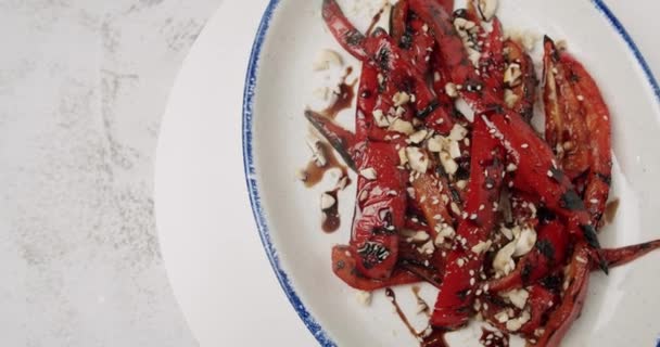 Жареный красный перец. вкусные овощи с орехами на вращающейся белой тарелке — стоковое видео