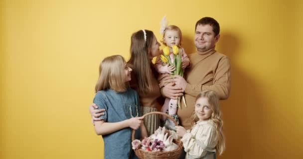 Мать-отец и дети обнимаются, весело проводят время и позируют на жёлтом фоне — стоковое видео