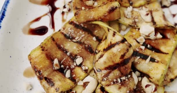 Calabacín a la parrilla con nueces listo para servir en el restaurante en el plato blanco — Vídeo de stock