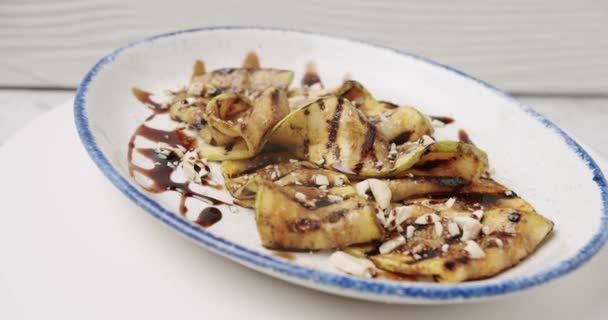Grilled courgette with nuts ready to serve in the restaurant on the white plate — Stock Video
