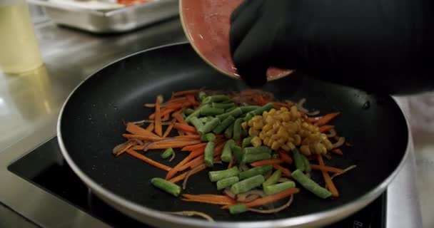 Приготовление овощей на сковороде на кухне, горох, морковь, кукуруза. — стоковое видео