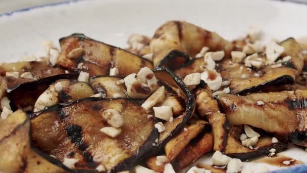 Grilled aubergine. delicious vegetables with nuts on a rotating white plate — Stock Video