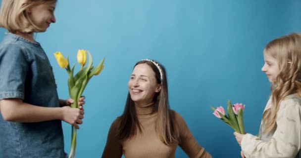 Sestry s tulipány květiny dávat mamince na modrém pozadí, Happy Mother. — Stock video