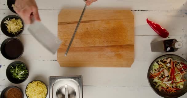 요리사들은 흰 식탁에서 일하고 재료를 갈 아서큰 칼을 날카롭게 한다. — 비디오