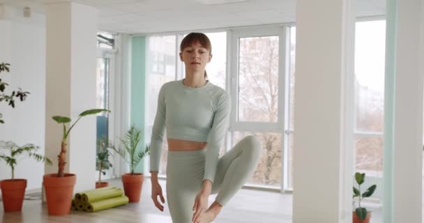 Jonge vrouw oefent een yoga in heldere studio 's, Utthita Hasta Padangusthasana — Stockvideo