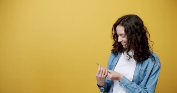 Joyeuse femme souriante posant avec une carte de crédit à la main, filmée en studio — Video