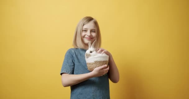 Підліток у блакитній сукні тримає кошик з кроликом у руці — стокове відео