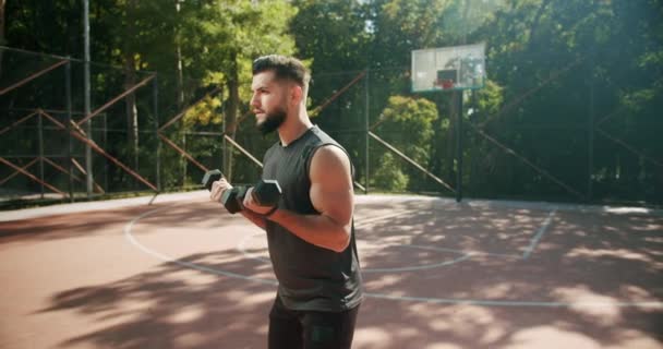 Sportieve man tilt gewichten met beide handen in een openbaar park, halter training — Stockvideo