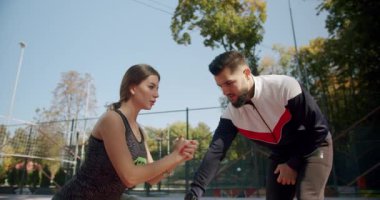 Koç dışarıda spor sahasında oturan güzel bir spor kadını eğitiyor.