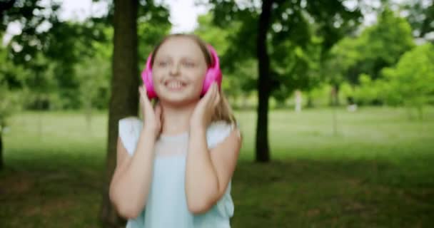 Gelukkig kind meisje in hoofdtelefoon dansen en springen tijdens het luisteren naar de muziek — Stockvideo