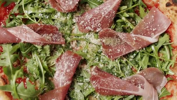 Close-up en zoom Pizza met prosciutto, arugula salade raket met ingrediënten. — Stockvideo