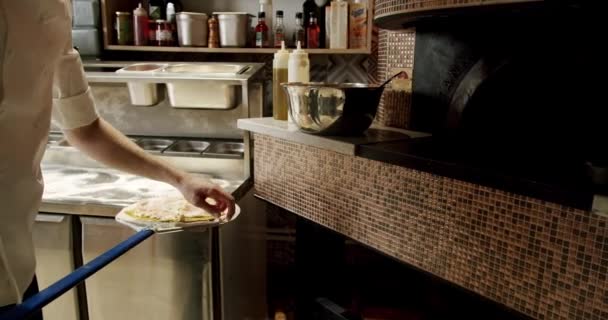 Preparando pizza en la cocina del restaurante. Pizza se coloca en el horno — Vídeo de stock