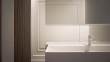 Beyaz minimalist tarzda banyo musluğu, lavabosu ve aynası olan evde..
