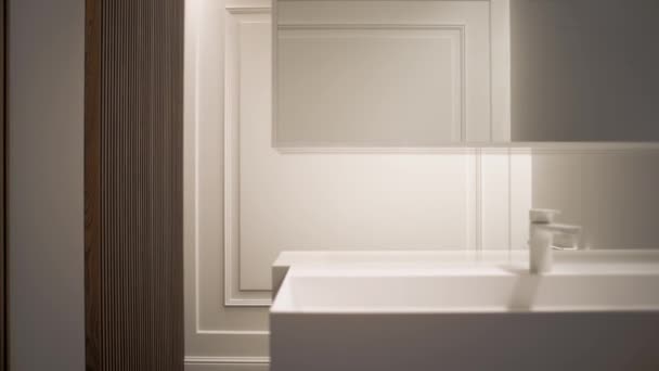 집 안에 수도꼭지가 있고 싱크대와 거울 이 있는 흰색 미니멀리즘적 인 욕실. — 비디오