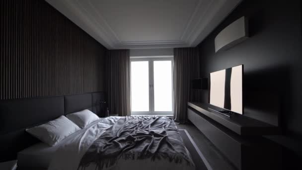 Echt modernes Schlafzimmer in dunklen Tönen mit Doppelbett, Vorhängen und großem Fernseher. — Stockvideo