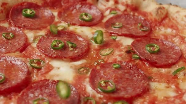 Close Up Hot green pepper falls on the pizza ready prepared with pepperoni. — Stock Video