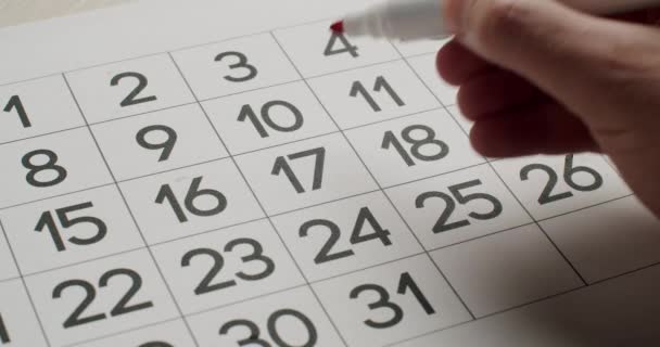 Mans hand Notez le 17ème jour sur le calendrier en papier à l'aide d'un stylo rouge. — Video
