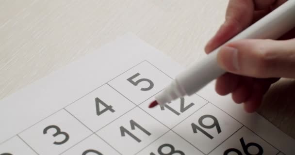 Mans hand Notez le 5ème jour sur le calendrier en papier à l'aide d'un stylo rouge. — Video