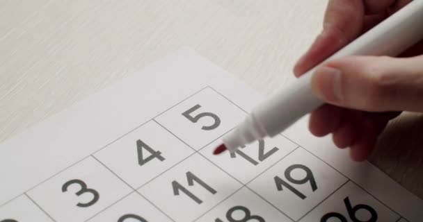 Mans hand Schrijf de 5e dag op de papieren kalender met een rode pen. — Stockvideo