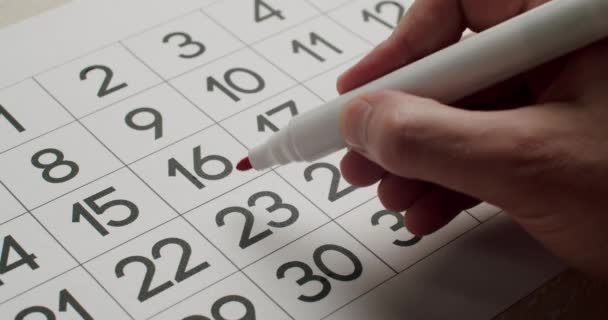 Mans hand Schrijf de 23e dag op de papieren kalender op met een rode pen. — Stockvideo