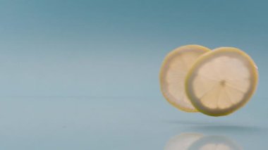 Yavaş Çekim Bir Limon Dilimi Mavi arka plana düşer, Limonlu Yumuşak İçki.