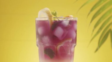 Yaz Kokteyli Limonata, nane ve buz küpleri sarı arka planda.