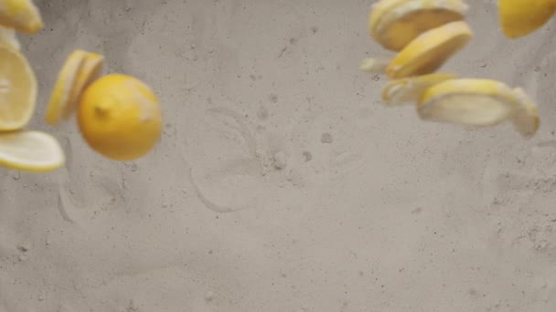 Limones enteros con trozos cortados de mosca de limón y chocan y caen sobre la arena. — Vídeo de stock