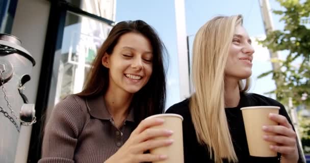 Två vänner njuter av en konversation med te och kaffe glasögon, förälskad utanför — Stockvideo