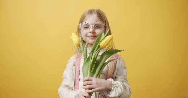 Frumoasă fată ține flori de lalele în mână ea zâmbește pe fundal galben — Videoclip de stoc