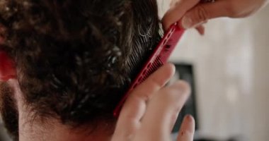 Yakın plan bir kuaför, kuaför ve stilistin hizmetini alıyor. Modern saç kesimi 