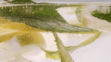 Nane ve buzlu su kabarcıkları içinde limon dilimi, soğuk limonata içmek.