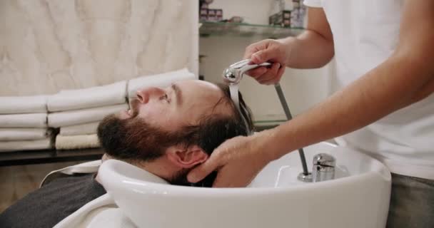 美容室の男はシャンプーと水で頭を洗う — ストック動画