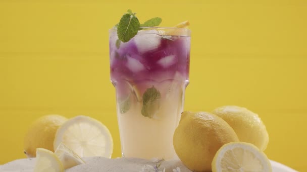 Summer Cocktail Glas limonade, munt en ijsblokjes op een gele achtergrond. — Stockvideo