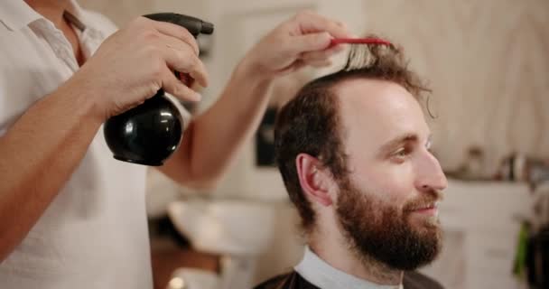 Fryzjer ustawia włosy przez spray i grzebie je. Korzystanie z usług fryzjera — Wideo stockowe