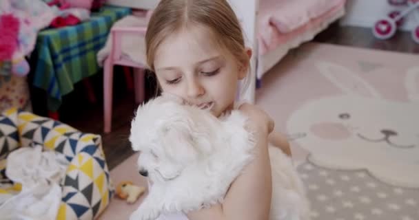 La niña de 7 años está jugando en casa con su cachorro. Es muy feliz.. — Vídeos de Stock