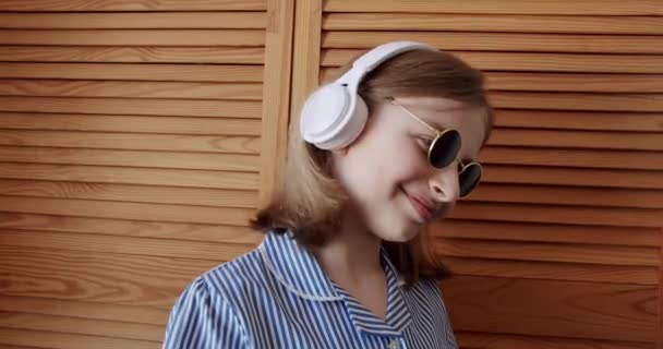 Jolie fille avec des lunettes de soleil rondes et écouteurs sans fil écouter de la musique — Video