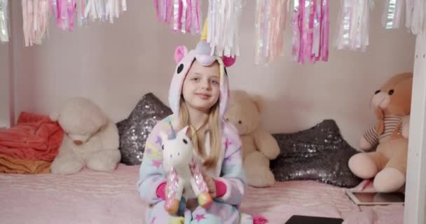Adorable niña de 7 años jugando con un disfraz de unicornio con muchos juguetes — Vídeo de stock