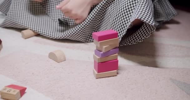 As crianças brincam com brinquedos sentam-se no tapete do chão em casa. jogo com blocos de madeira — Vídeo de Stock