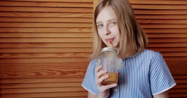 귀여운 십 대 소녀는 집에서 유리로 신선 한 오렌지 주스를 마시고, 맛있는 음료를 마신다.. — 비디오