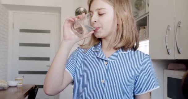 Linda adolescente bebiendo agua natural de vidrio en casa. agua natural — Vídeo de stock