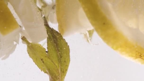 Slow Motion Macro shot van een citroenschijfje in waterbellen, Koude Limonade drinken — Stockvideo