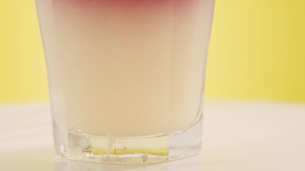 Літній коктейль Склянка лимонаду, м'яти і кубиків льоду на жовтому фоні . — стокове відео
