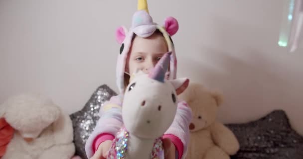 Adorável menina de 7 anos jogando em um traje de unicórnio com muitos brinquedos — Vídeo de Stock