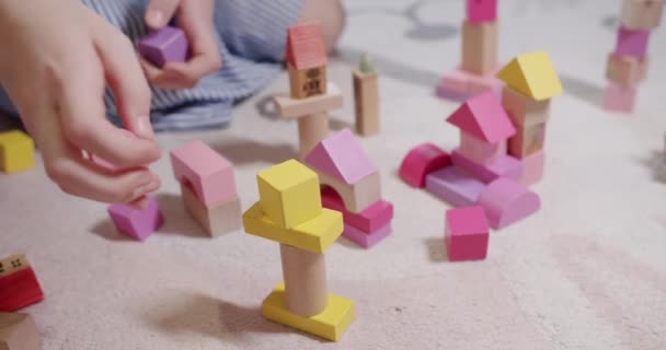 As crianças brincam com brinquedos sentam-se no tapete do chão em casa. jogo com blocos de madeira — Vídeo de Stock