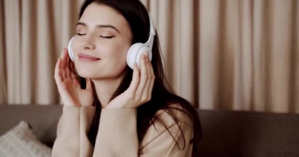 Mujer feliz joven consciente y sonrisa con el uso de auriculares inalámbricos blancos — Vídeos de Stock